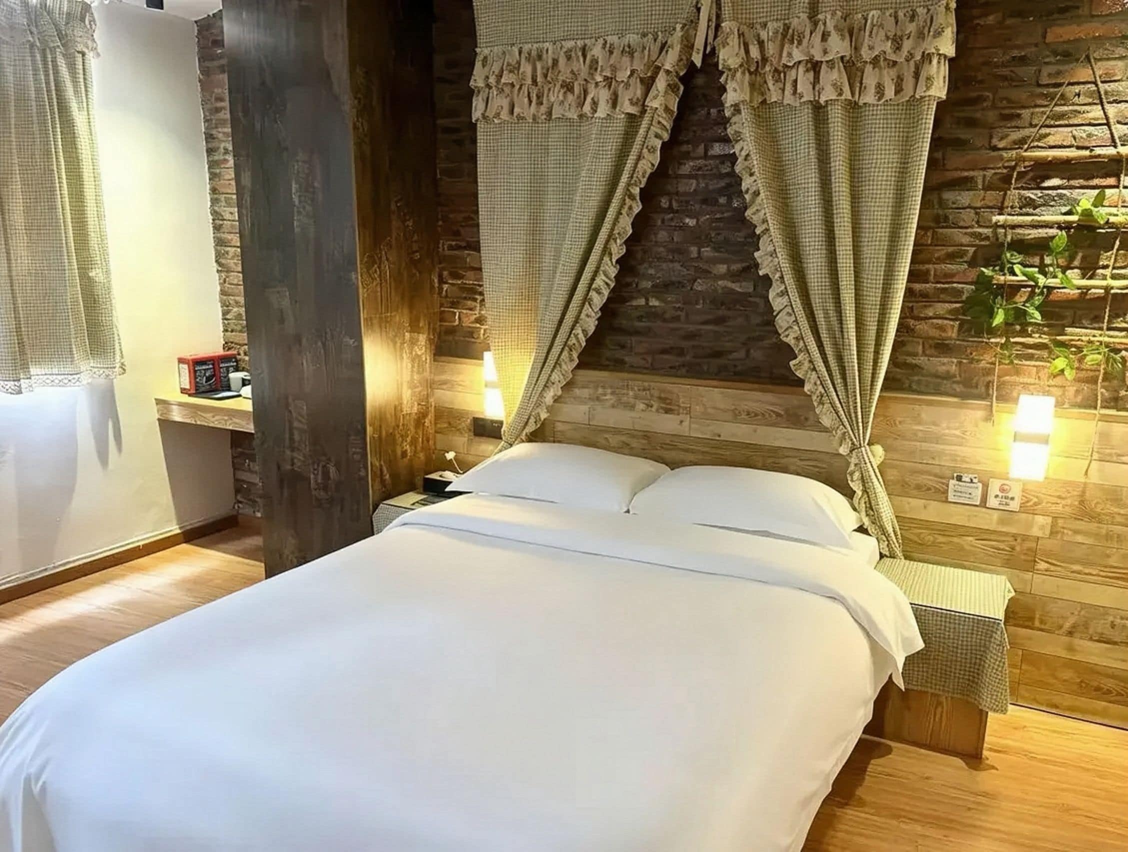 A bed with a white duvet, a wooden headboard, and a stone wall behind.