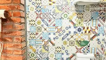 A bathroom with a tiled wall featuring a variety of patterns and a white toilet.