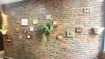 A brick wall with framed pictures and a hanging plant.