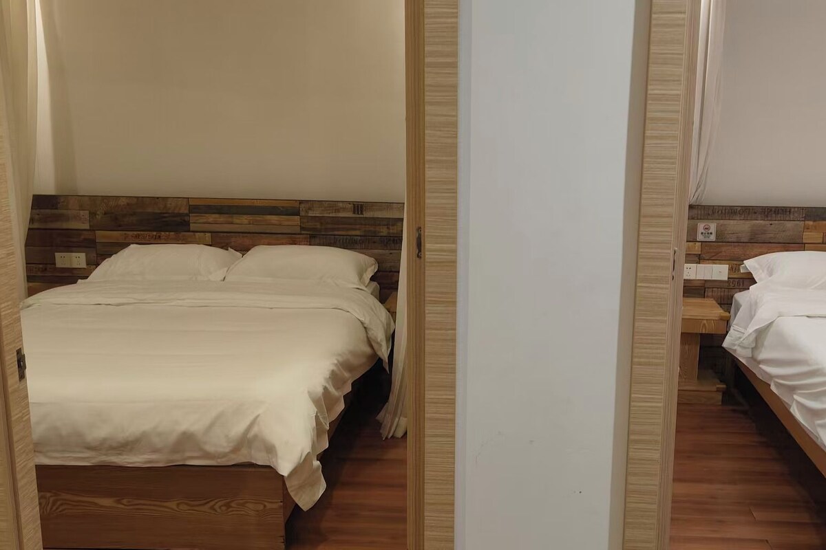 A mirrored view of a bedroom with two beds, wooden headboards, and a white wall.