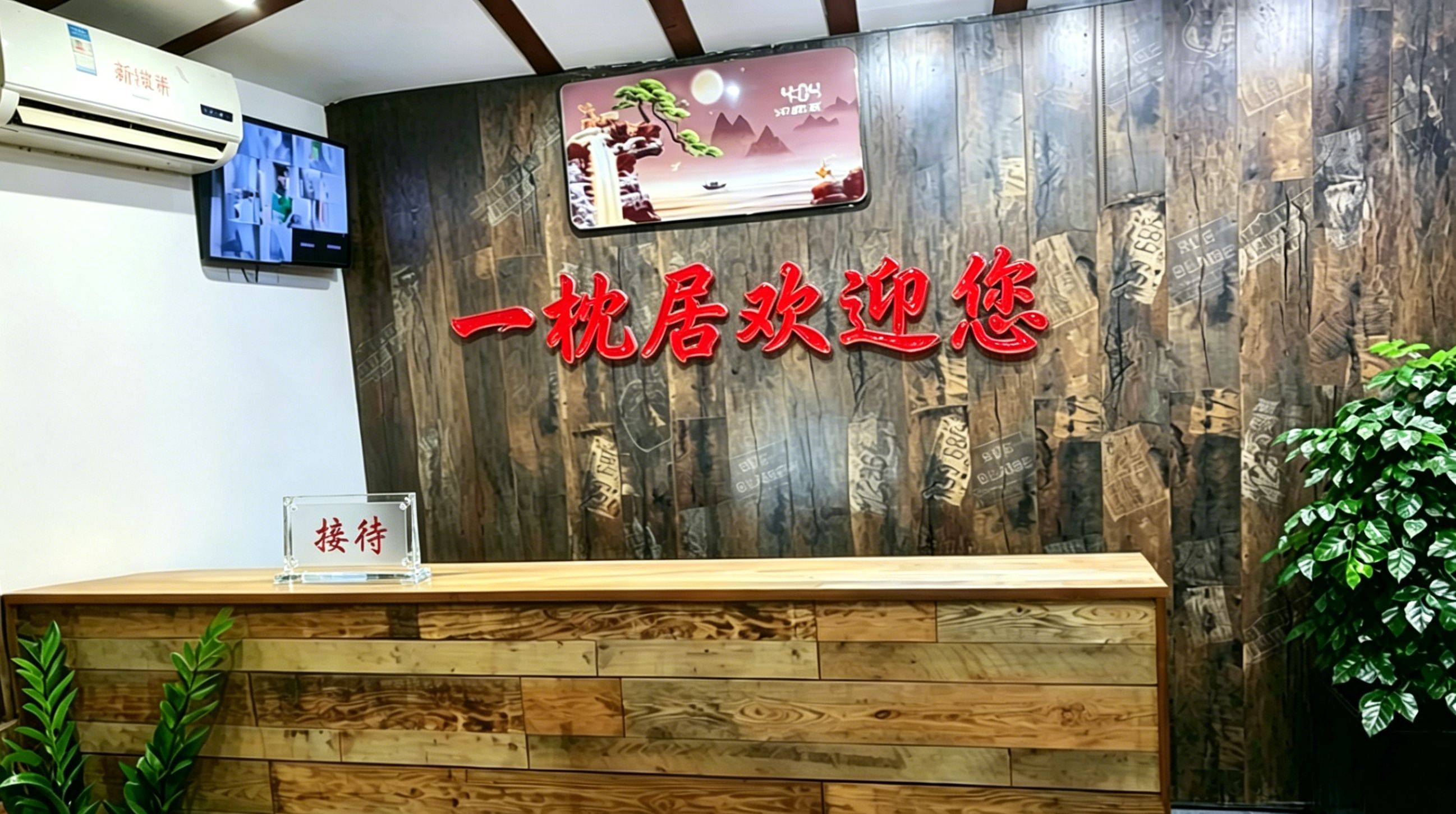 A reception desk with a wooden backdrop, a digital screen displaying a scenic image, and a sign with red Chinese characters.
