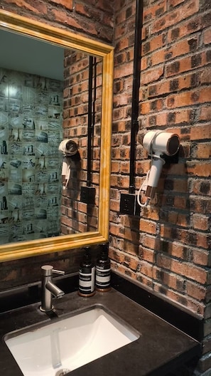A bathroom with a brick wall, a large mirror, a sink, and two hair dryers mounted on the wall. - Yizhenju Garden Residence Haizhu Wetland (Guang Zhou Shi)