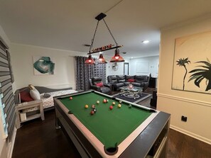 A pool table in a living room with a sofa and a coffee table. - Modern Gamer”s Haven - Relax & Play (Jackson)
