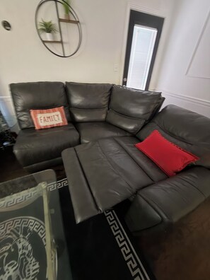 Een modulaire bank met een rood kussen en een kussen met de tekst 'FAMILY' in een woonkamer.