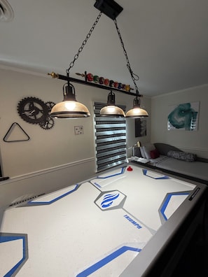 A pool table with a geometric design, a hanging light fixture, and a wall clock. - Modern Gamer”s Haven - Relax & Play (Jackson)