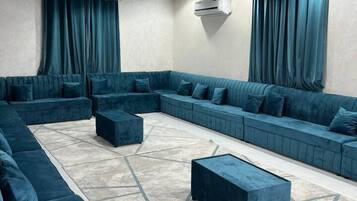 A modern lounge area with a sectional sofa, ottomans, and a patterned rug.