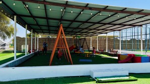 Un espace de jeux extérieur avec des balançoires, des toboggans et des bancs.