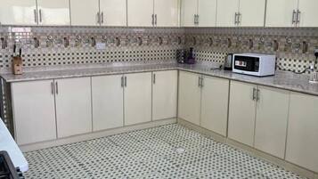Una cocina con armarios blancos, un microondas y un suelo estampado.