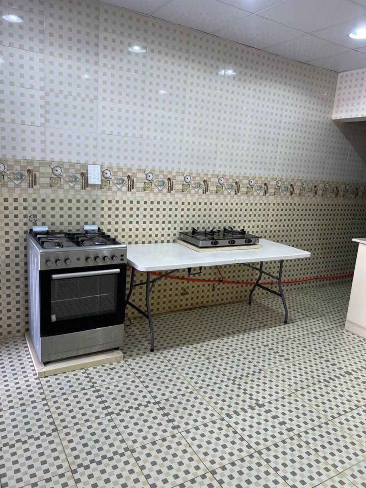 A kitchen with a gas stove, oven, and a white table.