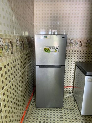 Una cocina con un refrigerador de acero inoxidable, paredes y piso de cerámica.
