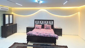 Une chambre à coucher moderne, avec un lit, des tables de chevet, une commode et un luminaire au plafond.