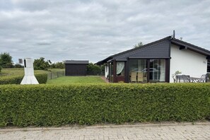 Een modern huis met een groot raam, een verzorgd gazon en een haag.