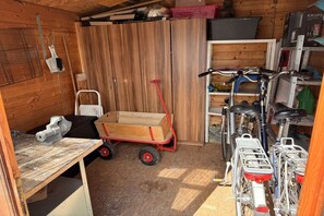 A compact room with a wooden floor, a small table, a red handcart, and bicycles. - Dike Break J3||Eckwarderhörne (Eckwarderhörne)