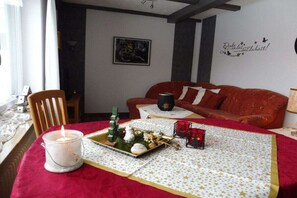 A cozy living room with a red sofa, a table with a candle, and a Christmas tree decoration.