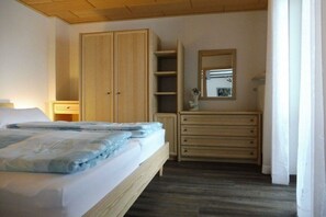 A bedroom with a bed, a wardrobe, a dresser, and a mirror.