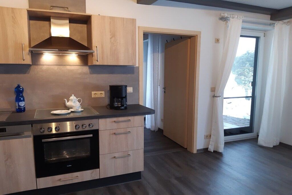 A modern kitchen with wooden cabinets, a built-in oven, and a coffee maker.
