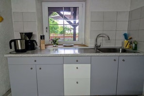 Een keuken met een raam, een spoelbak en kasten.