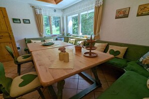 A dining area with a wooden table, green upholstered chairs, and a green sofa. - Holiday home Fehrengrund (Fehrenbach)