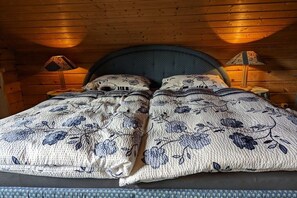 A bed with floral bedding, two bedside lamps, and a wooden ceiling. - Holiday home Fehrengrund (Fehrenbach)