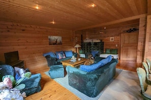 A cozy log cabin interior with a sofa set, a wooden coffee table, and a fireplace. - Holiday home Fehrengrund (Fehrenbach)