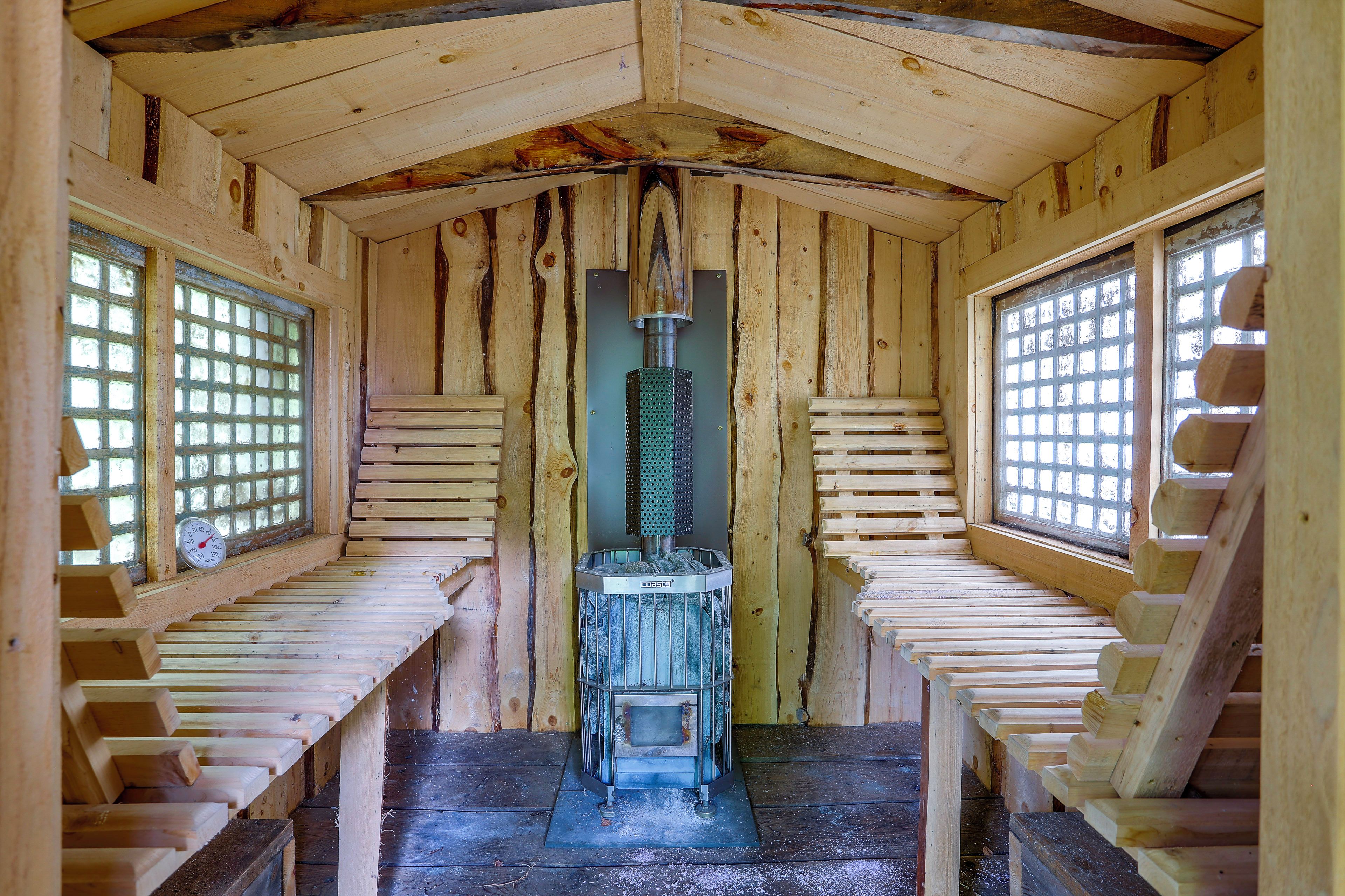 A wooden cabin with a central heating system, wooden benches, and a window with a grid pattern.