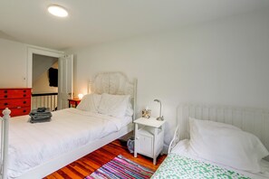Ein Schlafzimmer mit zwei Betten, einem Nachttisch, einer Kommode und einem roten Sessel.