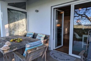 An outdoor dining area with a wooden table, chairs, and a fruit bowl. - Michaela holiday apartment (Heiligenberg)