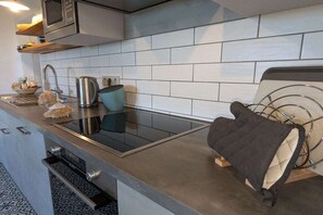 Eine moderne Küche mit Spüle aus Edelstahl, Wasserkocher und Mikrowelle.