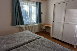 Ein Schlafzimmer mit Bett, Schreibtisch und Kleiderschrank.