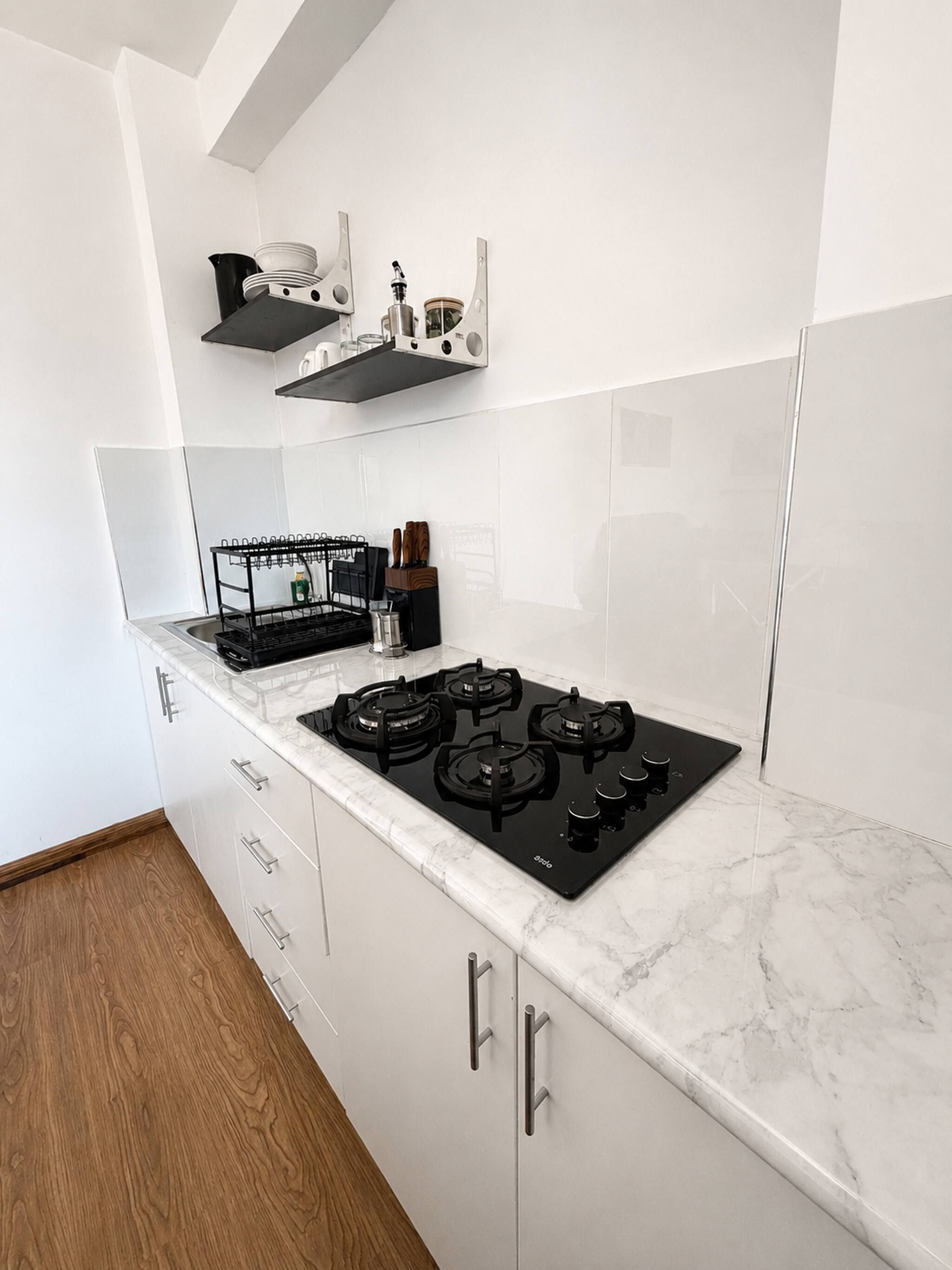 A kitchen with a black stove, white cabinets, and a wooden floor.