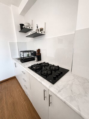 A kitchen with a black stove, white cabinets, and a wooden floor. - Urubamba 2 bedrooms, terraces and views (Urubamba)