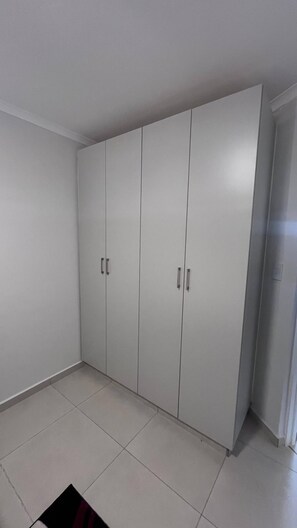 Ein Zimmer mit großem Kleiderschrank, Fliesenboden und einer Tür rechts.