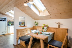 A dining area with a wooden table, benches, and a skylight above. - Oven bench directly on Lake Chiemsee (Chieming)