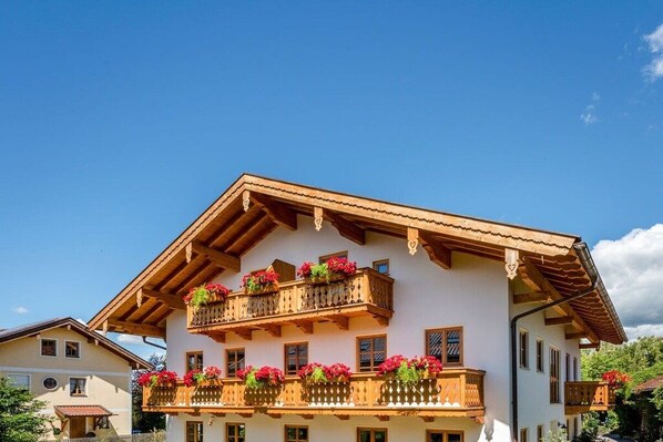 A two-story building with wooden balconies adorned with flowers. - Oven bench directly on Lake Chiemsee (Chieming)