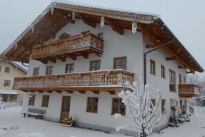 A two-story chalet with a balcony, wooden railings, and a snow-covered roof. - Oven bench directly on Lake Chiemsee (Chieming)