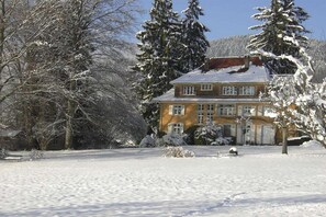 A two-story house with a snow-covered roof and surrounding trees. - 2 Alpenblick - Steineckhof (Schopfheim)