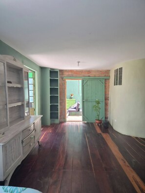 A room with a wooden floor, a green door, and a view through an open door to another room. - House for 10 in an oak forest  Santa Elena (Santa Elena)
