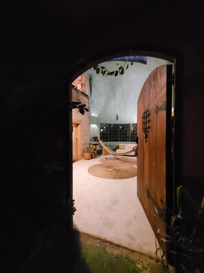 Ein Innenraum mit einer großen Holztür, einer Hängematte und einem runden Teppich.