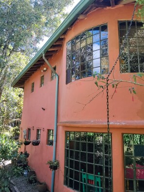 A two-story building with multiple windows, a curved roof, and a green chair outside. - House for 10 in an oak forest  Santa Elena (Santa Elena)