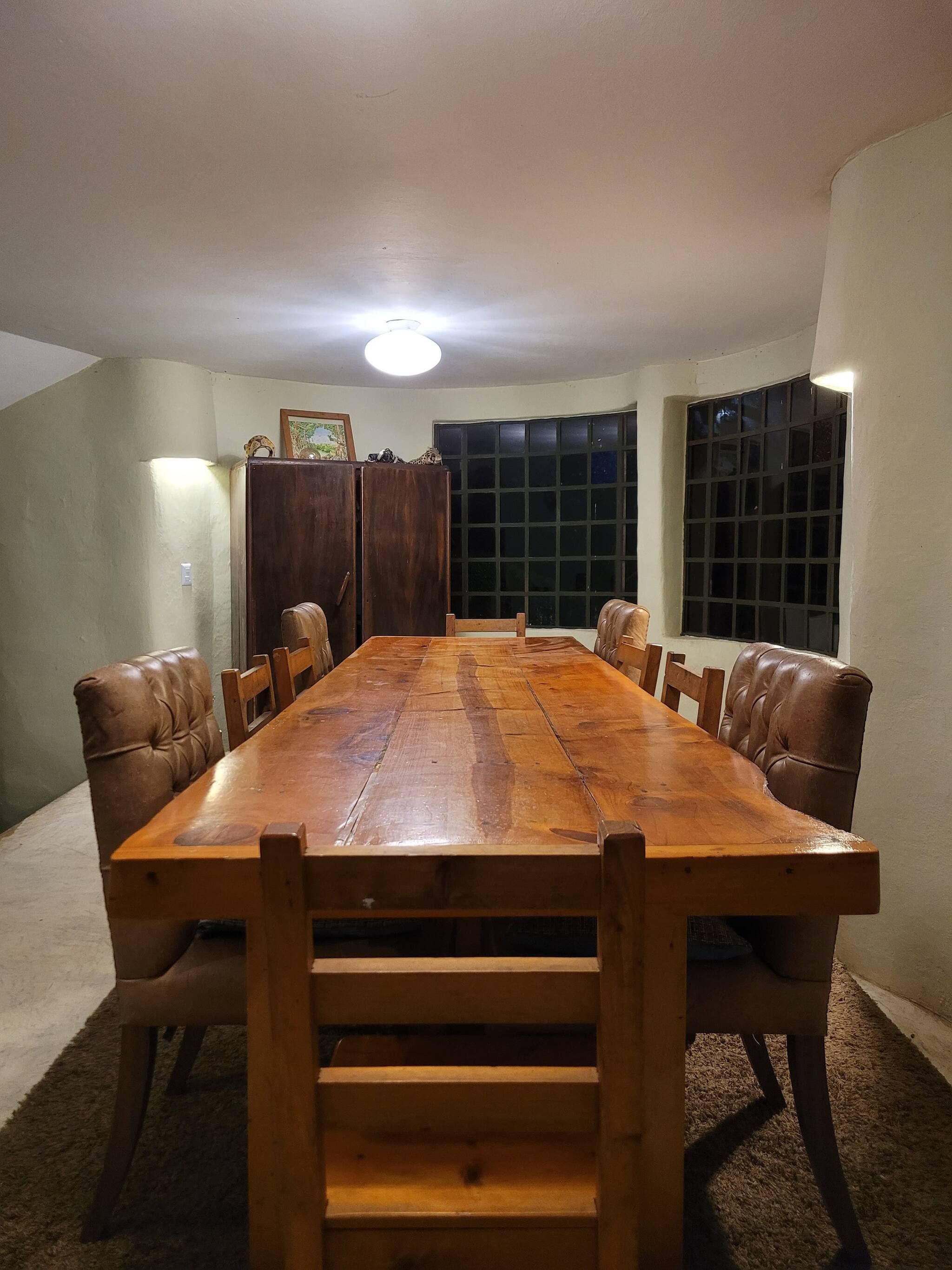 Ein rechteckiger Esstisch mit sechs Stühlen, ein Holzschrank und ein Fenster mit Jalousien.