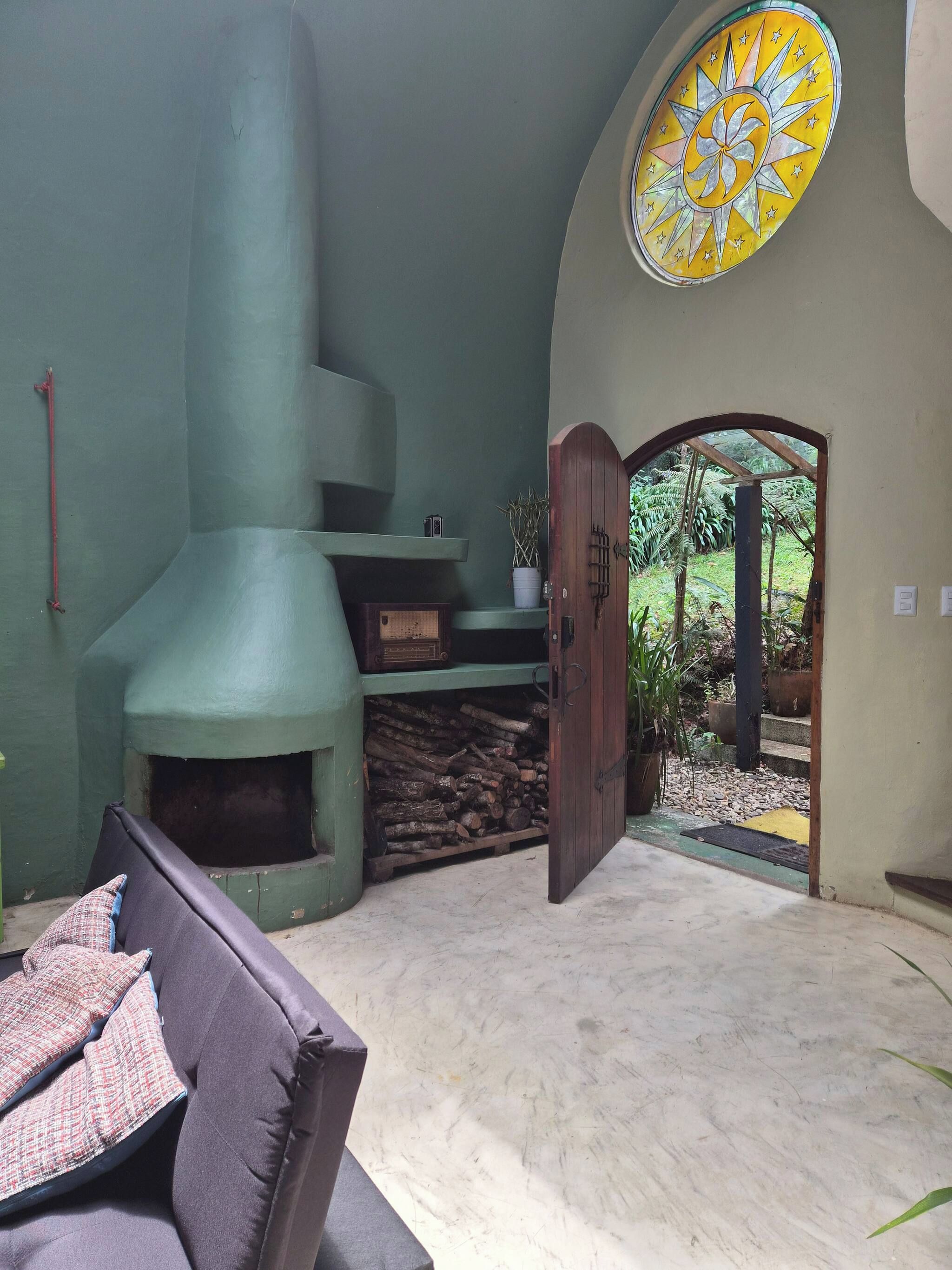 A room with a fireplace, a door leading to an outdoor area, and a circular window.