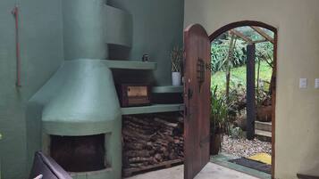 A room with a fireplace, a door leading to an outdoor area, and a circular window.