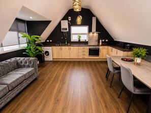 Una cocina moderna con comedor, piso de madera y sofá gris.