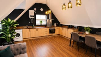 A modern kitchen with wooden cabinets, a built-in oven, and a dining area with a table and chairs.
