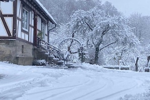 Paisagem coberta de neve com um edifício de estilo arquitetônico tradicional, incluindo uma escadaria e corrimão de metal.