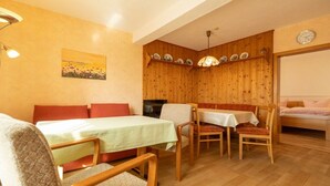 Een gezellige kamer met een bed, een eettafel met stoelen, een bank en een wandplank met borden.