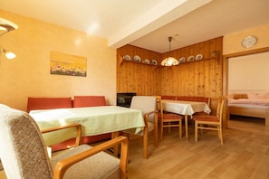Quarto aconchegante com uma cama, uma mesa de jantar com cadeiras, um sofá e uma estante com pratos.