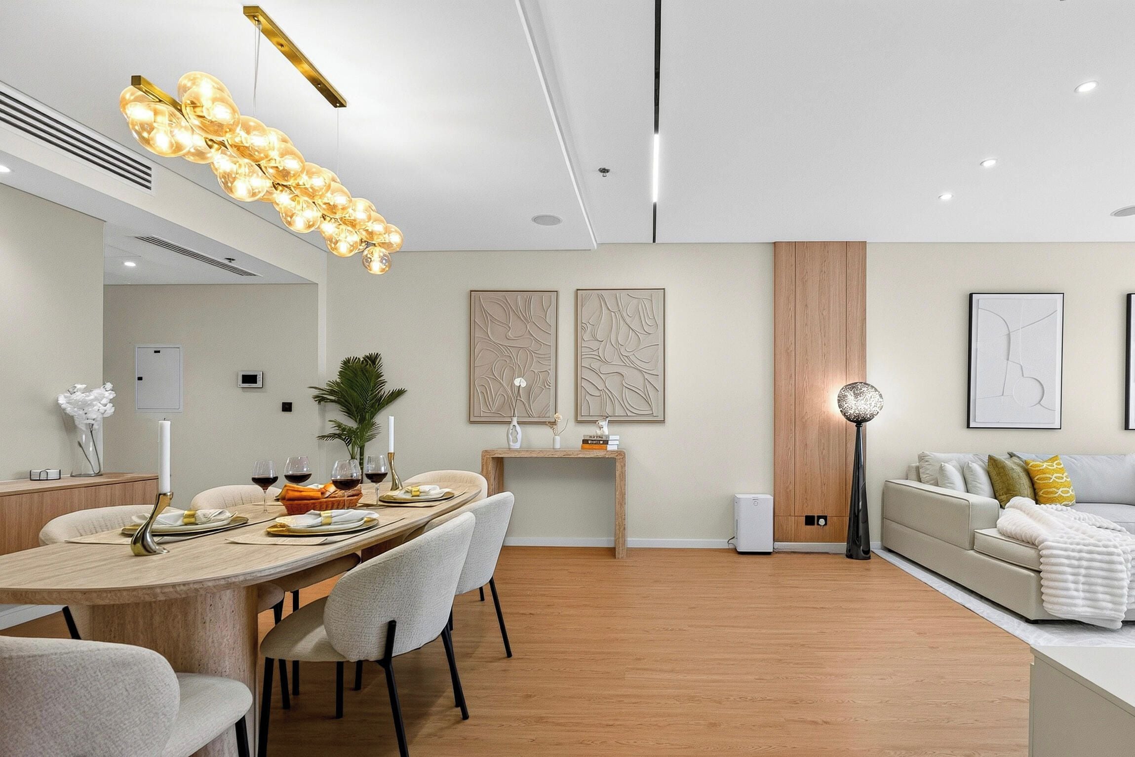 A modern living room with a dining area, wooden flooring, and contemporary decor.