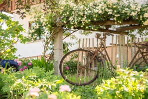 A bicycle leaning against a wooden fence in a garden with flowering plants and a tree. - Holiday apartment in Kappelrodeck with Wi-Fi (Kappelrodeck)