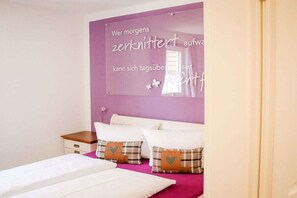 A bedroom with a bed, two pillows, a nightstand, and a wall with a message in German. - Child-friendly holiday home ALB-Traum (Hayingen)